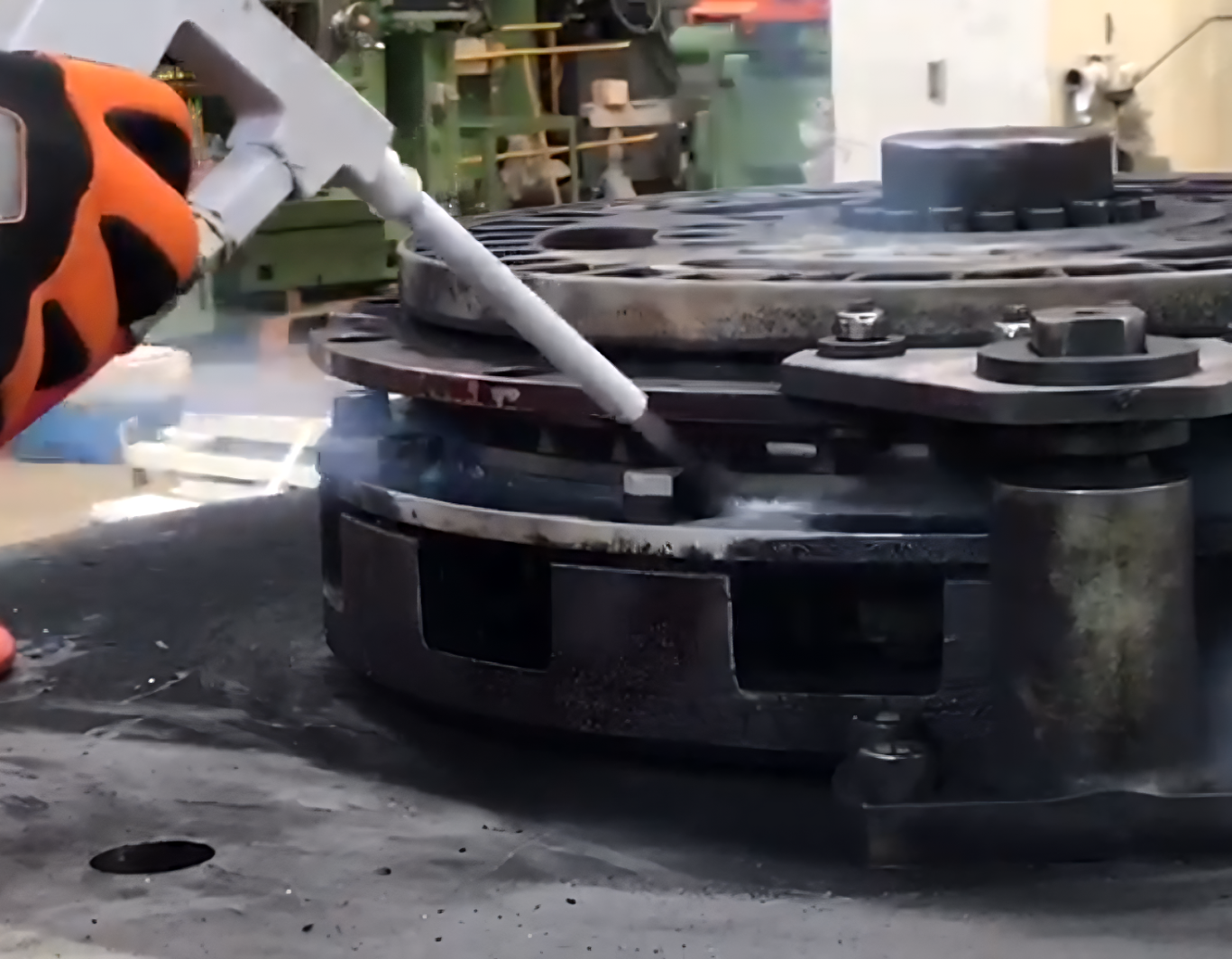 Arbeiter führt Eisstrahlen an einem Metallbauteil in einer Industriehalle durch 