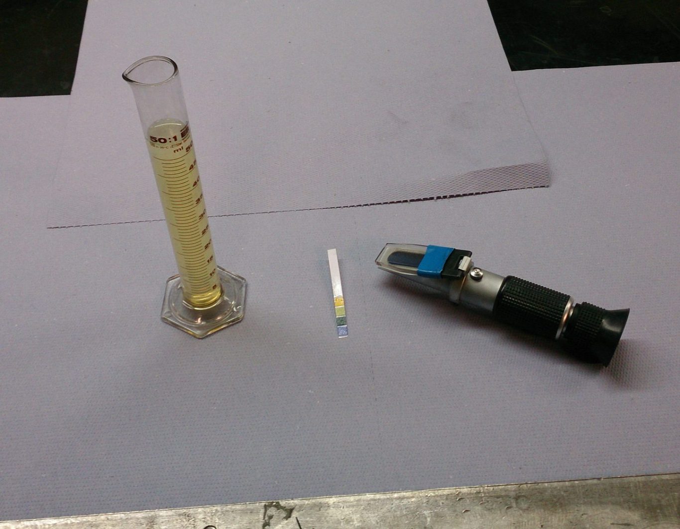 Messzylinder, pH-Teststreifen und Refraktiometer zur Analyse und Kontrolle von Kühlschmierstoff