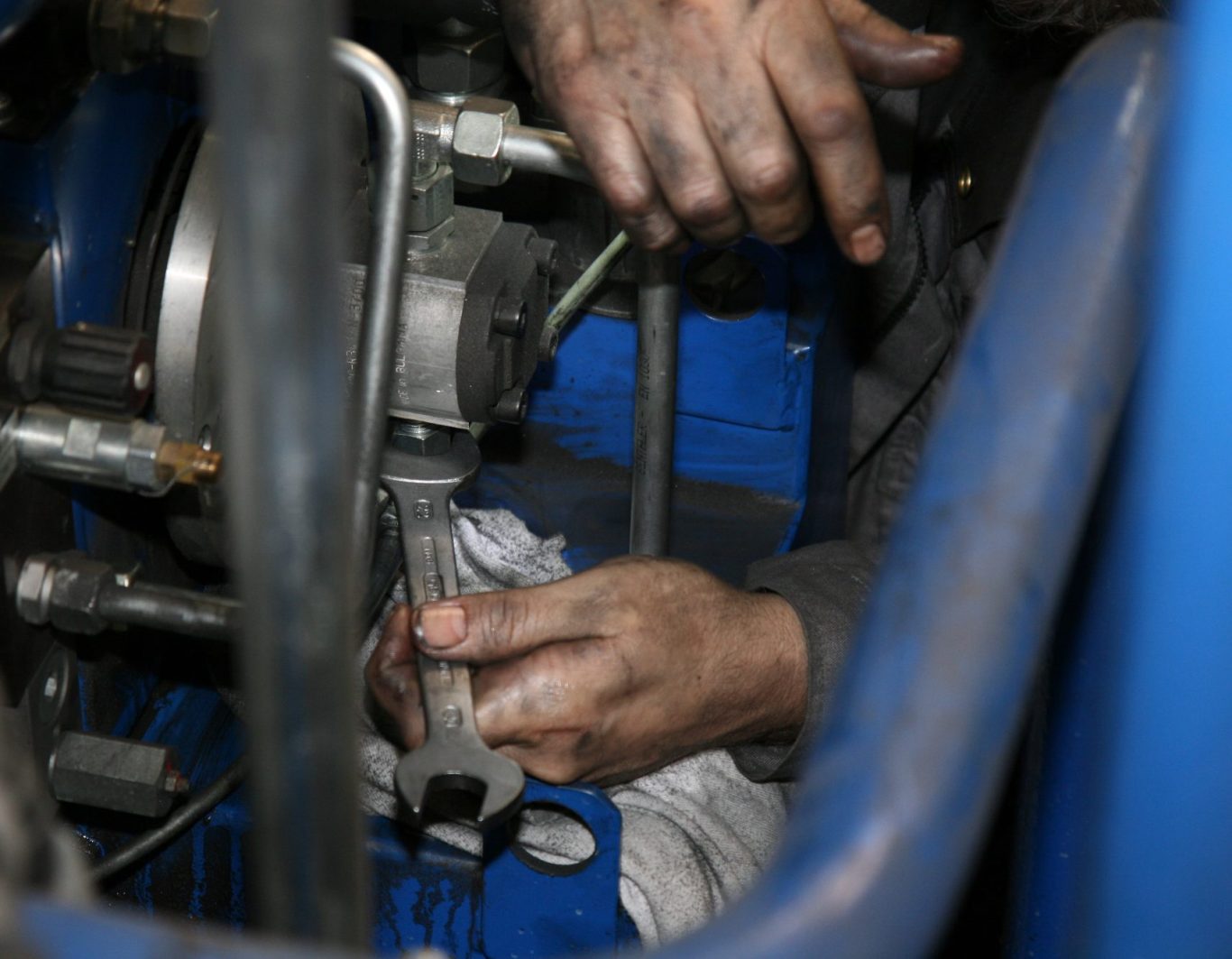 Ein Mitarbeiter führt Wartungsarbeiten mit Werkzeug an einem Maschinenbauteil durch